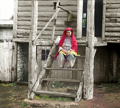 Bashkir woman in a folk costume sitting on the stairs of her wooden house, Ural Mountains, Russian Empire by Sergey Prokudin Gorsky
